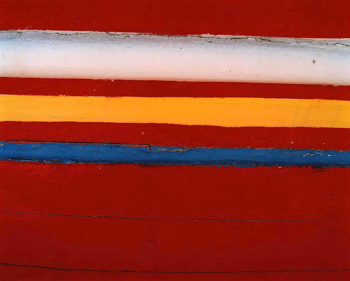 Abstract close-up of red wood with white, yellow and blue stripes, art exhibition in Mykonos, Greece