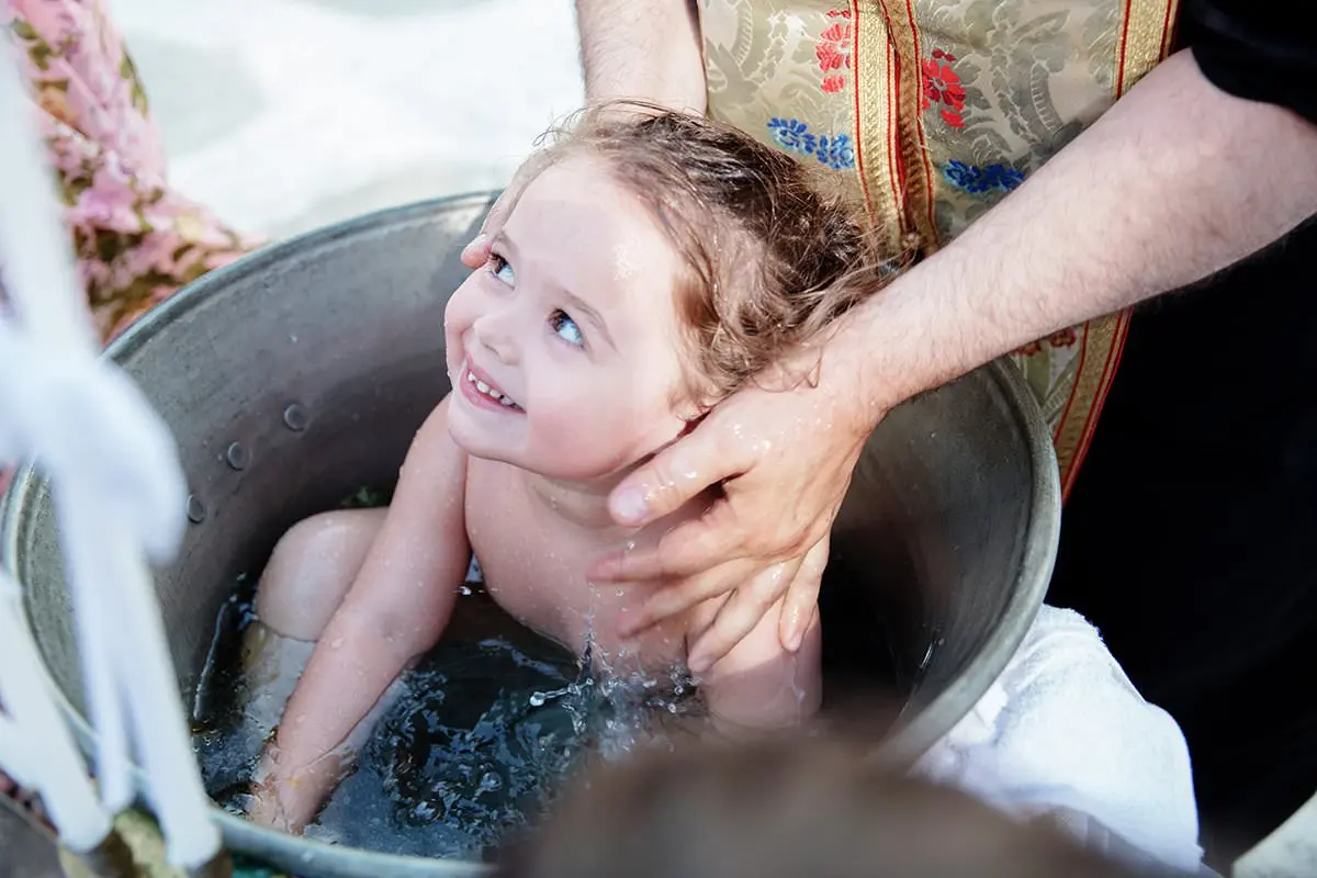 Greek Orthodox baptism ceremony at silver font in Mykonos, Greece