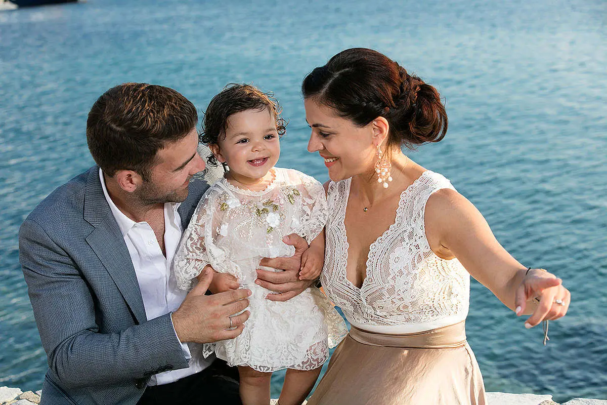 Baptism portrait against rustic red shutters in Mykonos, Greece