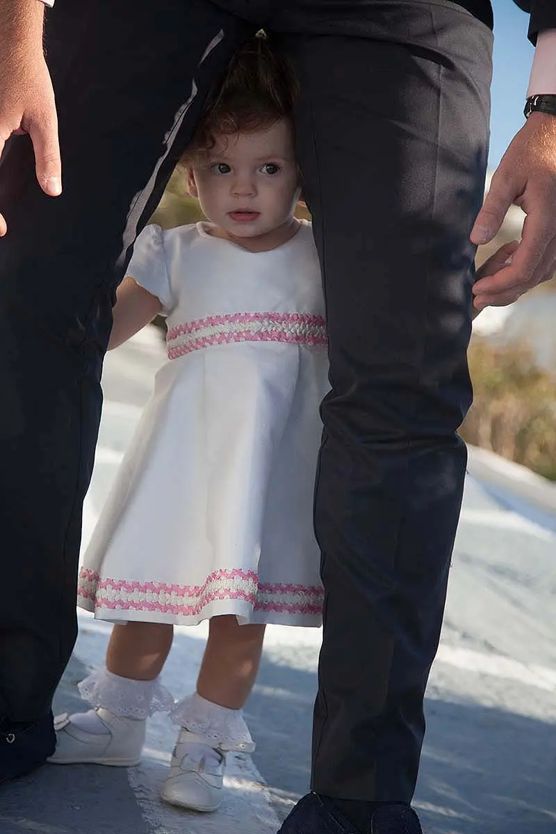 Playful child baptism portrait in a Mykonos alley, Greece