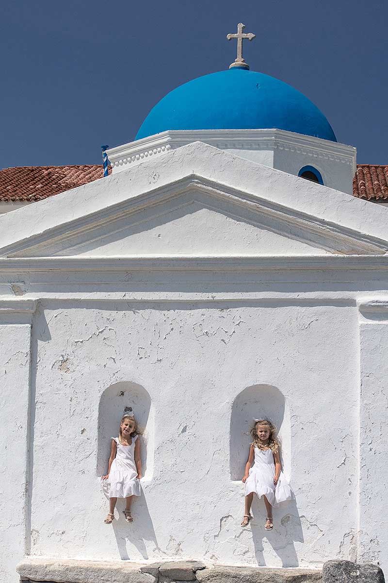 Blue dome chapel baptism portrait against Cycladic architecture in Mykonos, Greece