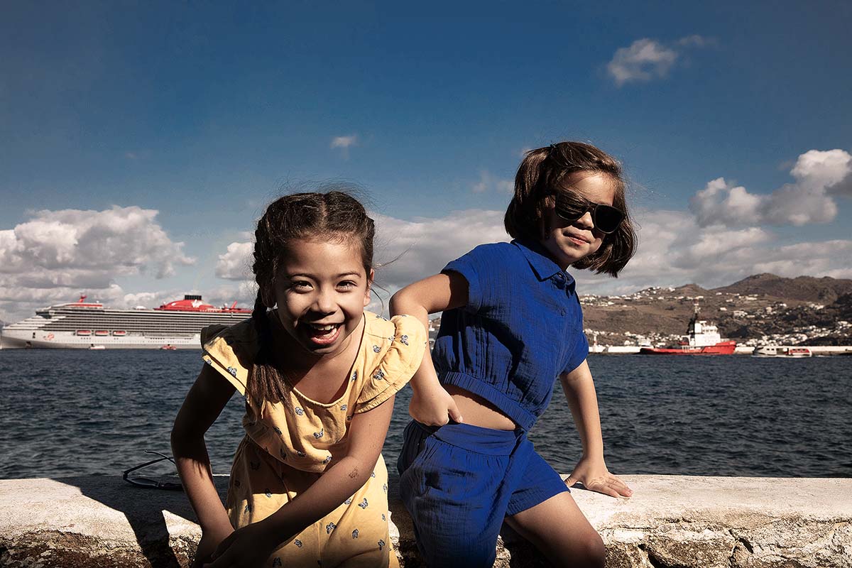 Children portrait at Mykonos harbor with cruise ship in Greece