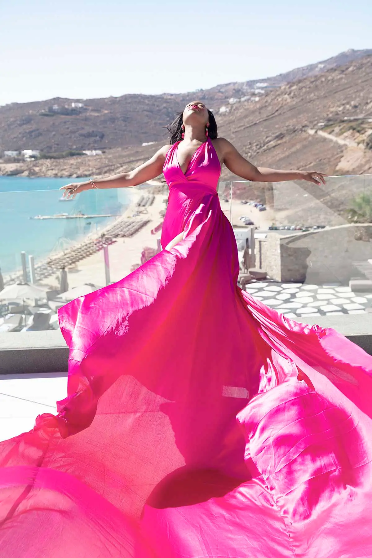 Sunlit amber flying dress by the Aegean sea, photography in Mykonos, Greece