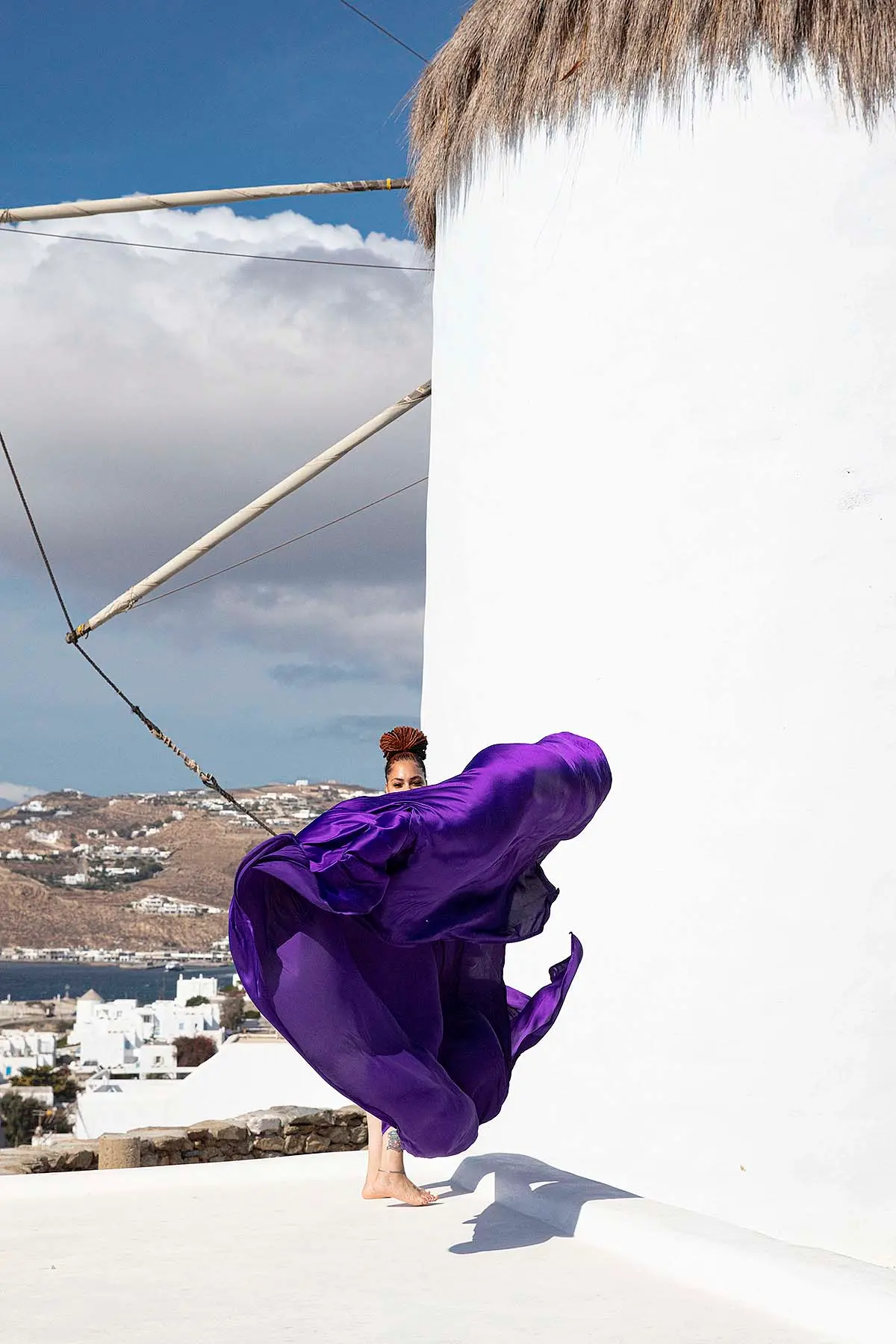 Sunlit copper flying dress by Cycladic walls, photography in Mykonos, Greece