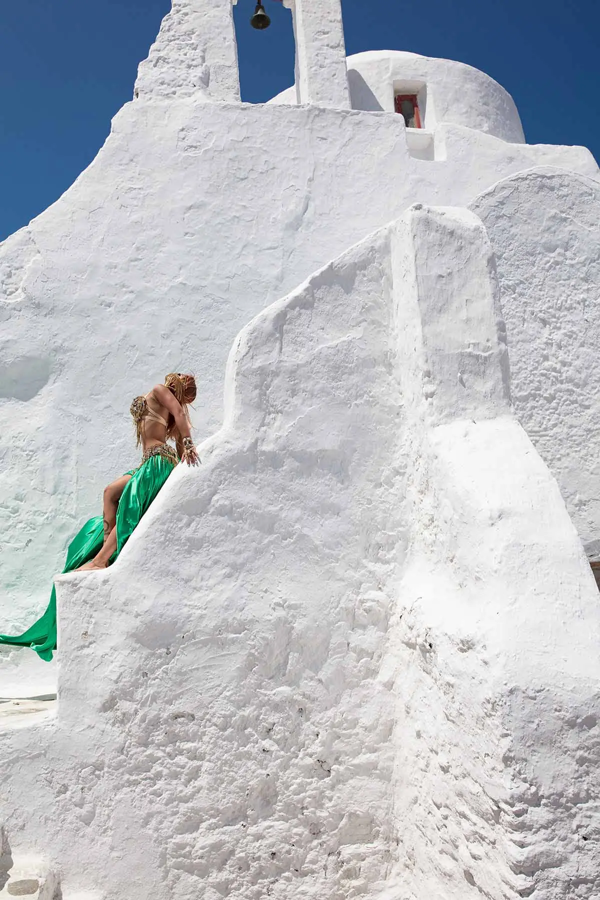 Sunlit coral flying dress in a Mykonos alley, photography in Mykonos, Greece
