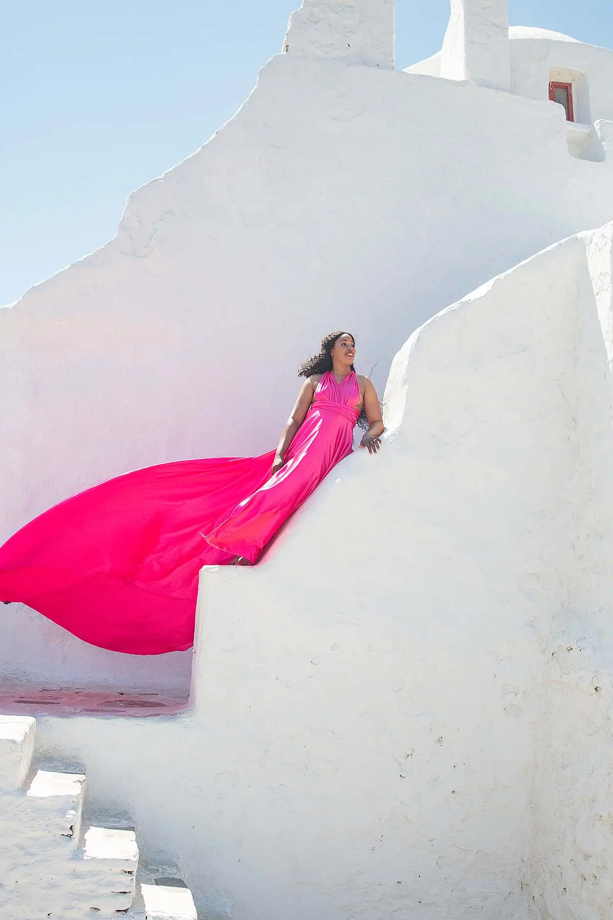 Sunlit coral flying dress by the Aegean sea, photography in Mykonos, Greece