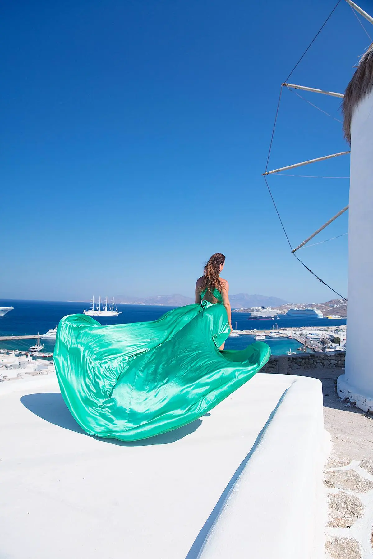 Sunlit coral flying dress by Cycladic walls, photography in Mykonos, Greece
