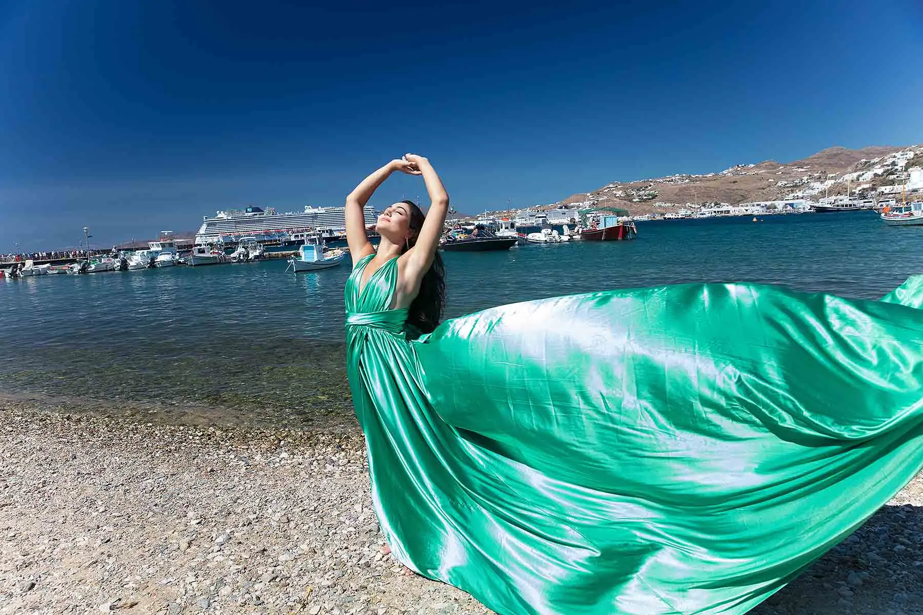Sunlit emerald flying dress in a Mykonos alley, photography in Mykonos, Greece