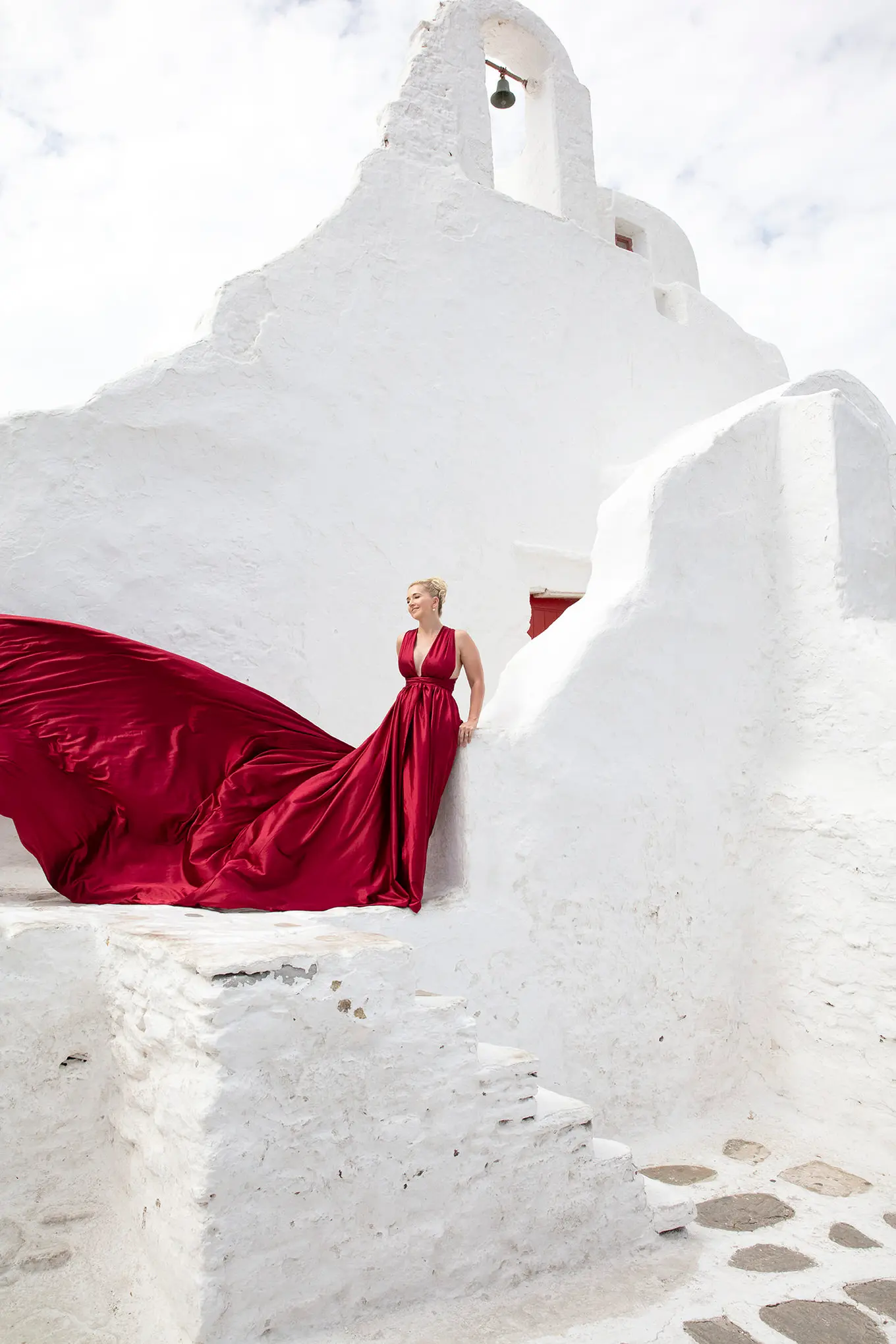 Sunlit fuchsia flying dress at Mykonos blue dome chapel on a sunlit terrace, photography in Mykonos, Greece