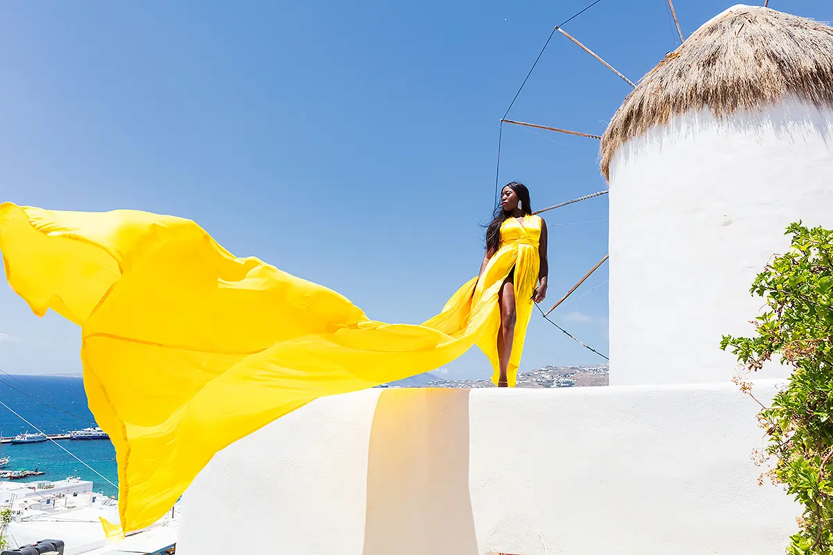 Sunlit gold flying dress at a Mykonos windmill, photography in Mykonos, Greece