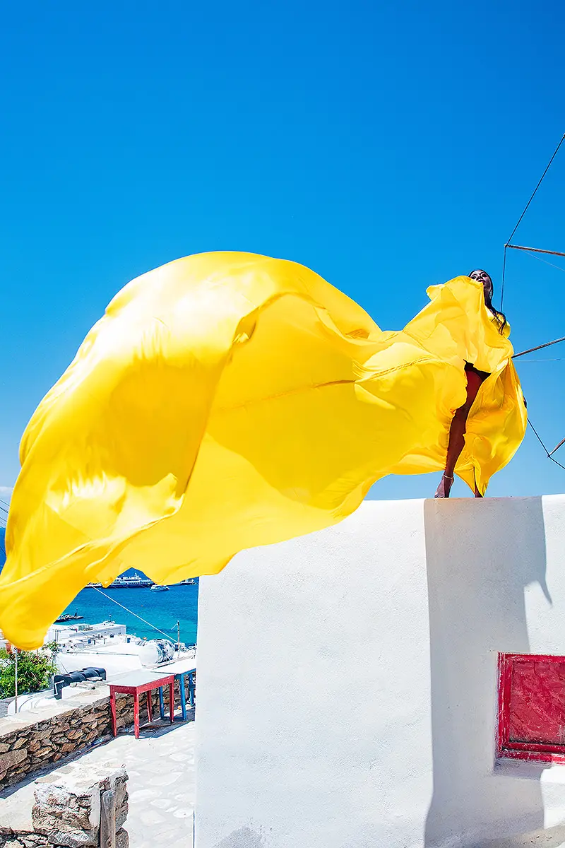 Sunlit gold flying dress on a Mykonos rooftop, photography in Mykonos, Greece