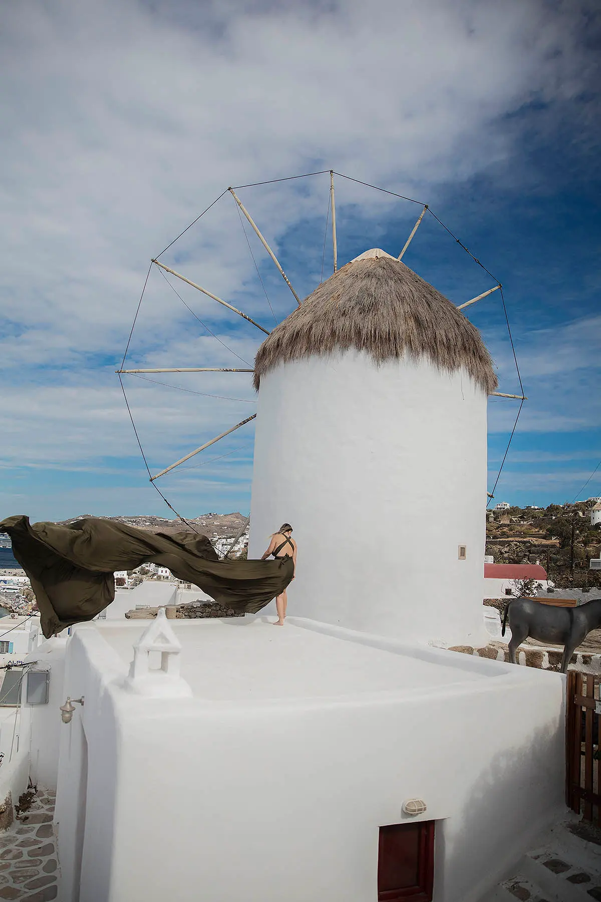 Sunlit ivory flying dress at a Mykonos windmill, photography in Mykonos, Greece