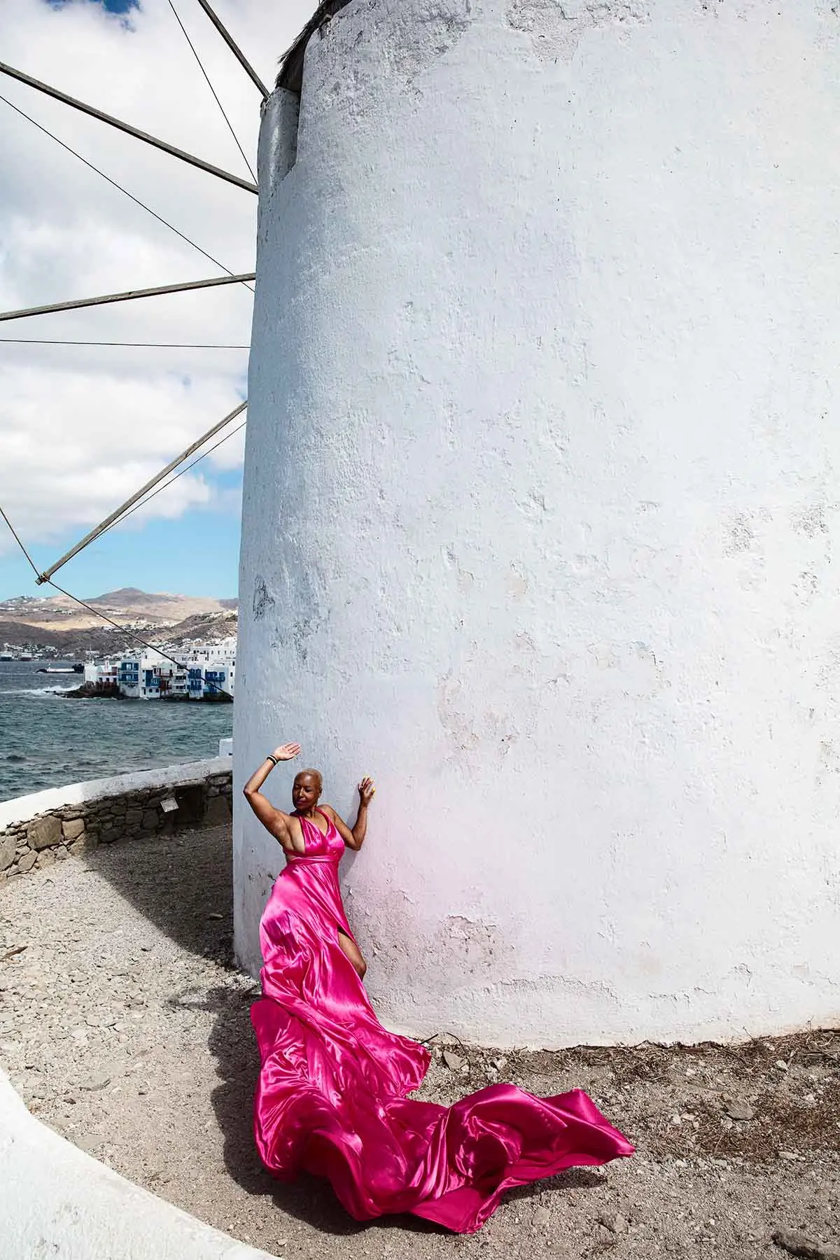 Sunlit magenta flying dress in a Mykonos alley, photography in Mykonos, Greece