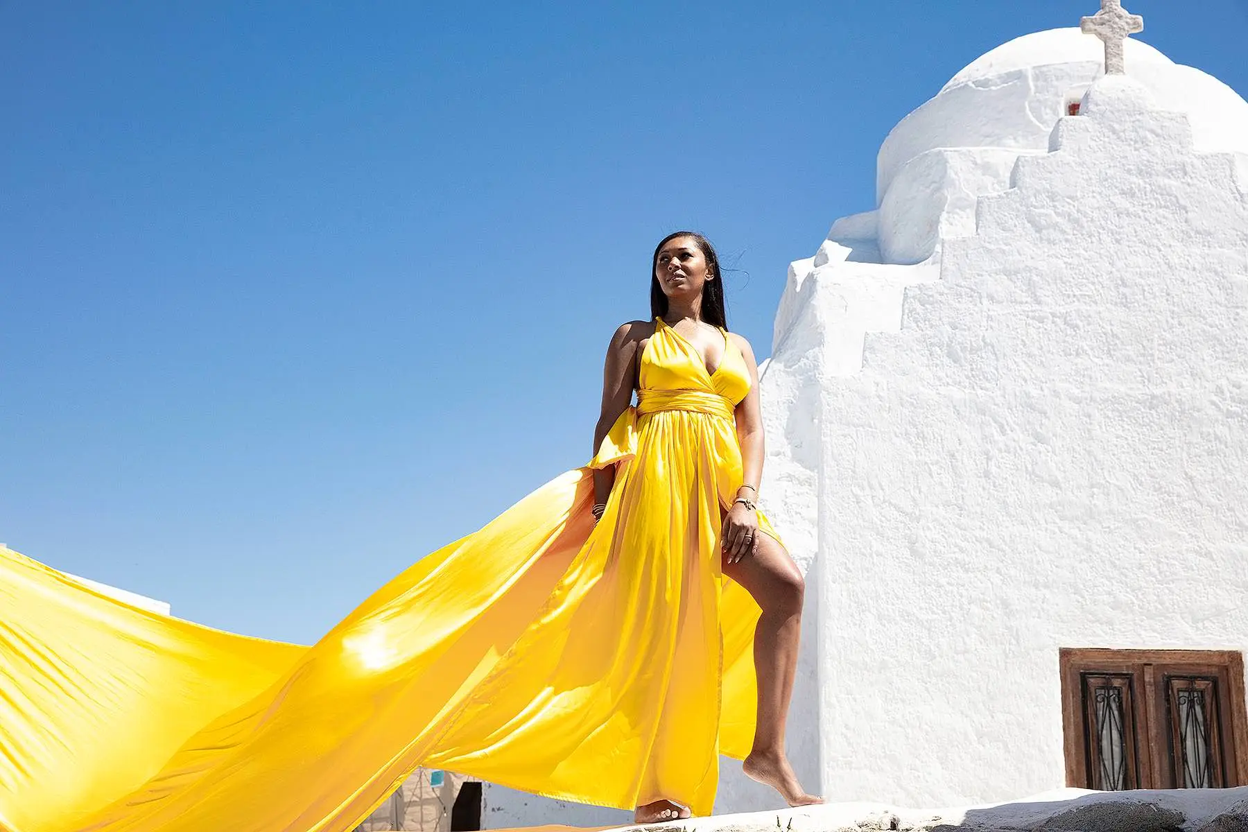 Sunlit magenta flying dress by Cycladic walls, photography in Mykonos, Greece