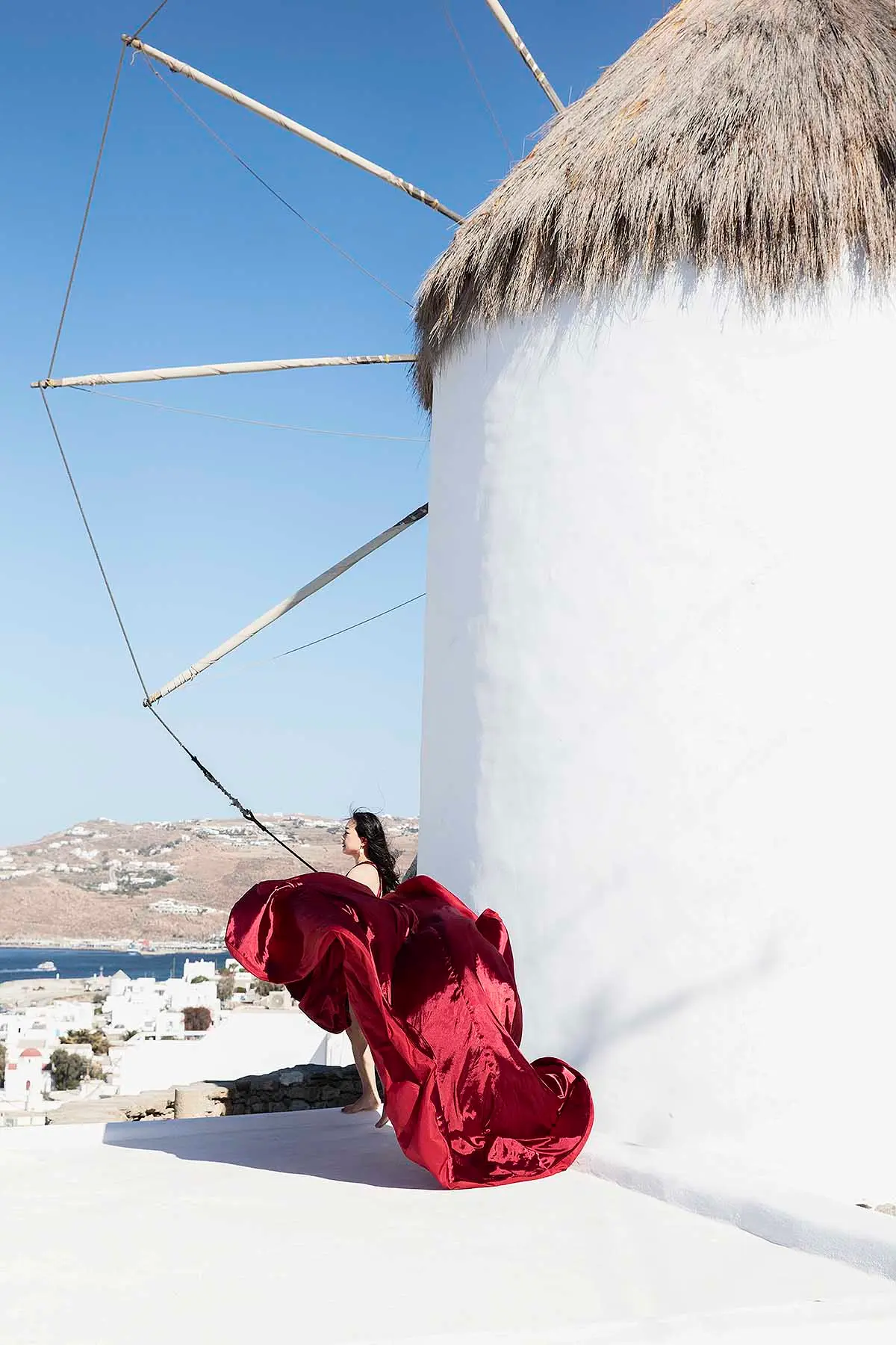 Sunlit magenta flying dress on a sunlit terrace, photography in Mykonos, Greece