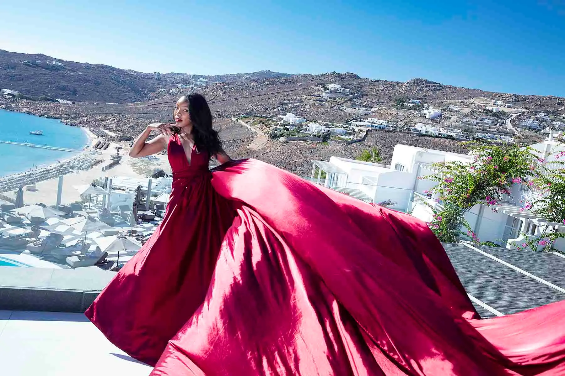 Sunlit magenta flying dress near a whitewashed chapel, photography in Mykonos, Greece