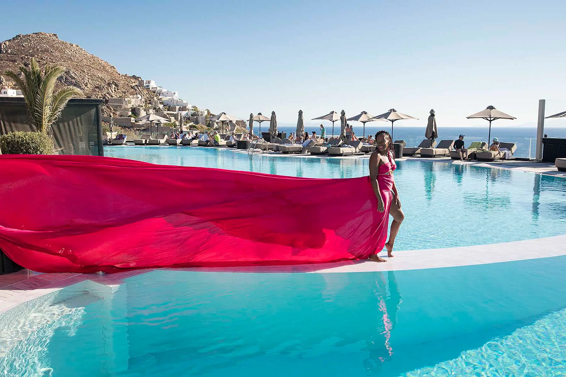 Sunlit noir alley flying dress by Cycladic walls, photography in Mykonos, Greece