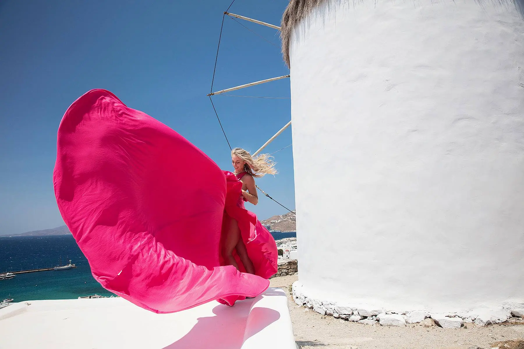 Sunlit noir alley flying dress near a whitewashed chapel, photography in Mykonos, Greece