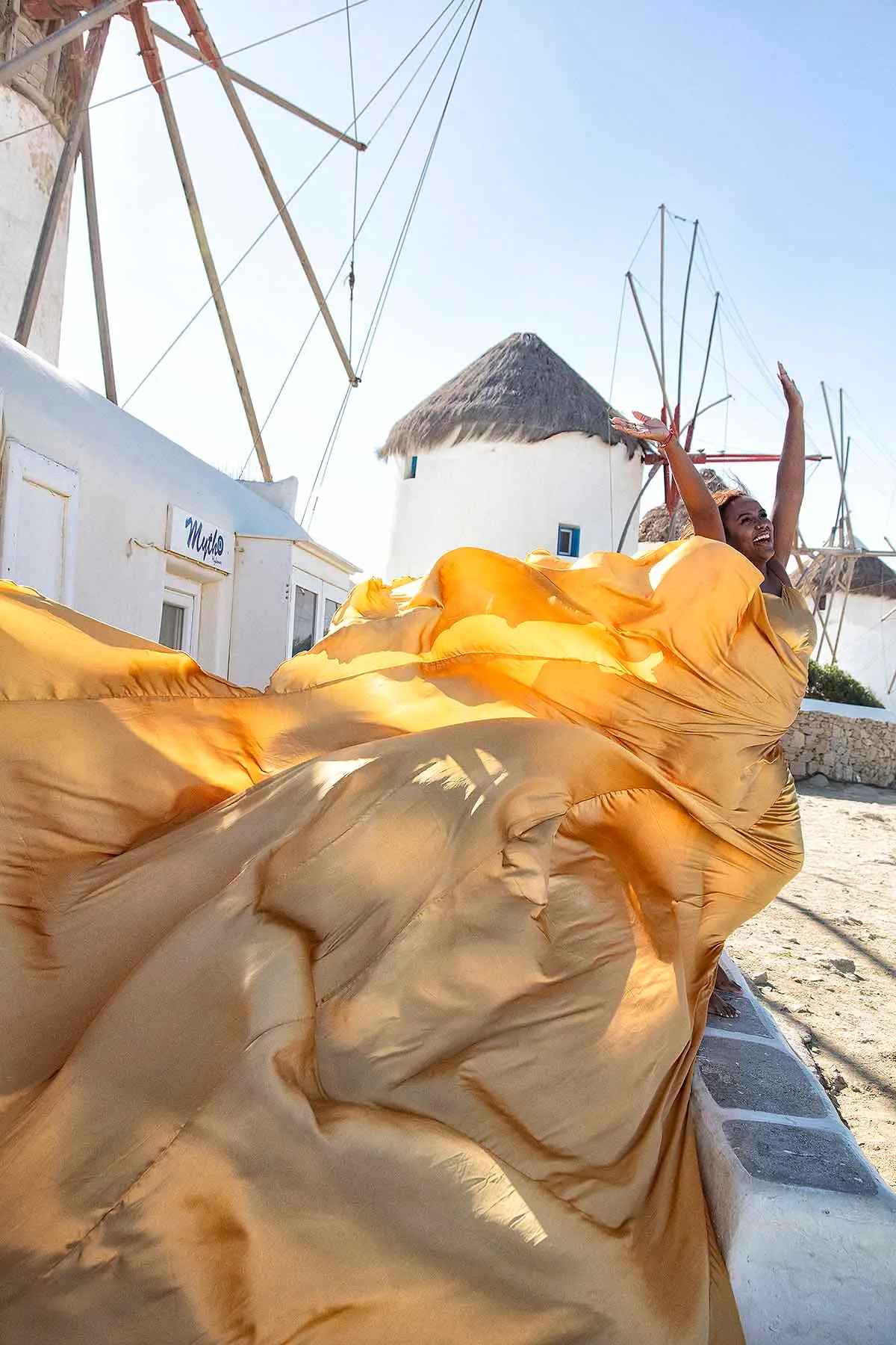 Sunlit pearl flying dress in a Mykonos alley, photography in Mykonos, Greece