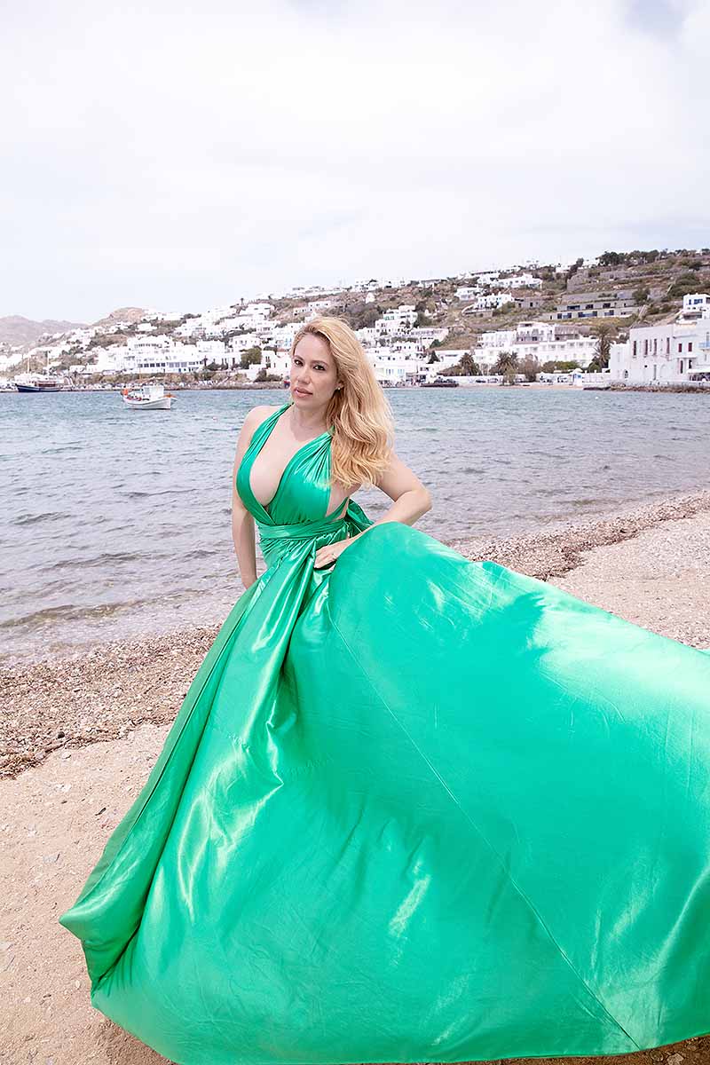 Sunlit red satin flying dress at Mykonos windmill on a sunlit terrace, photography in Mykonos, Greece