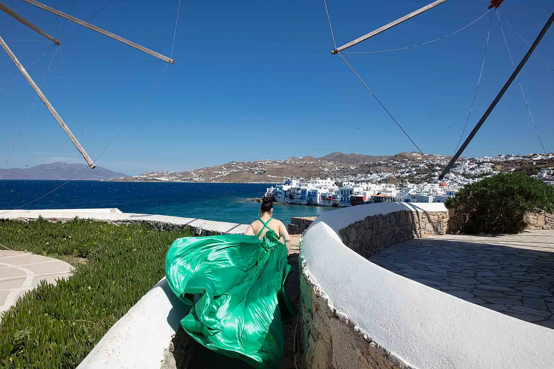Sunlit rose flying dress in a Mykonos alley, photography in Mykonos, Greece