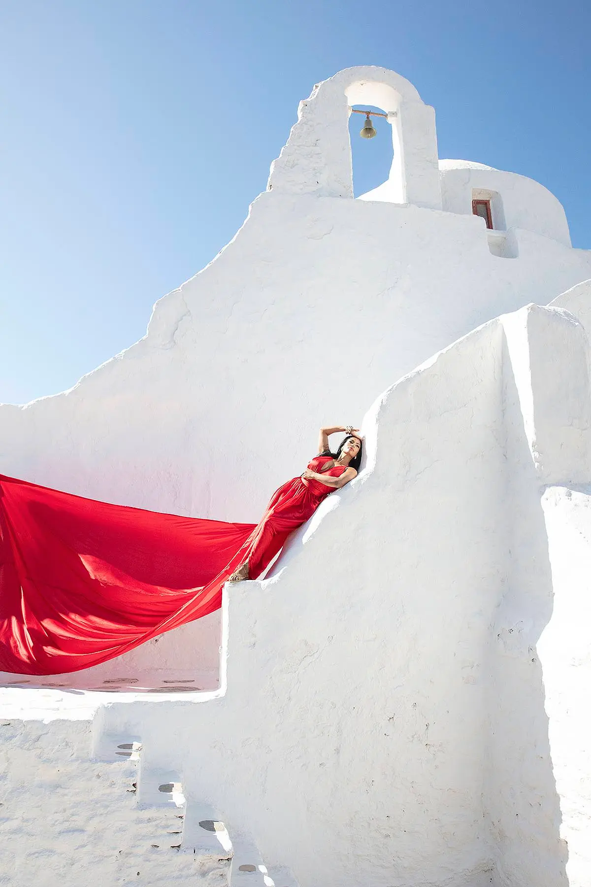 Sunlit rose flying dress near a whitewashed chapel, photography in Mykonos, Greece