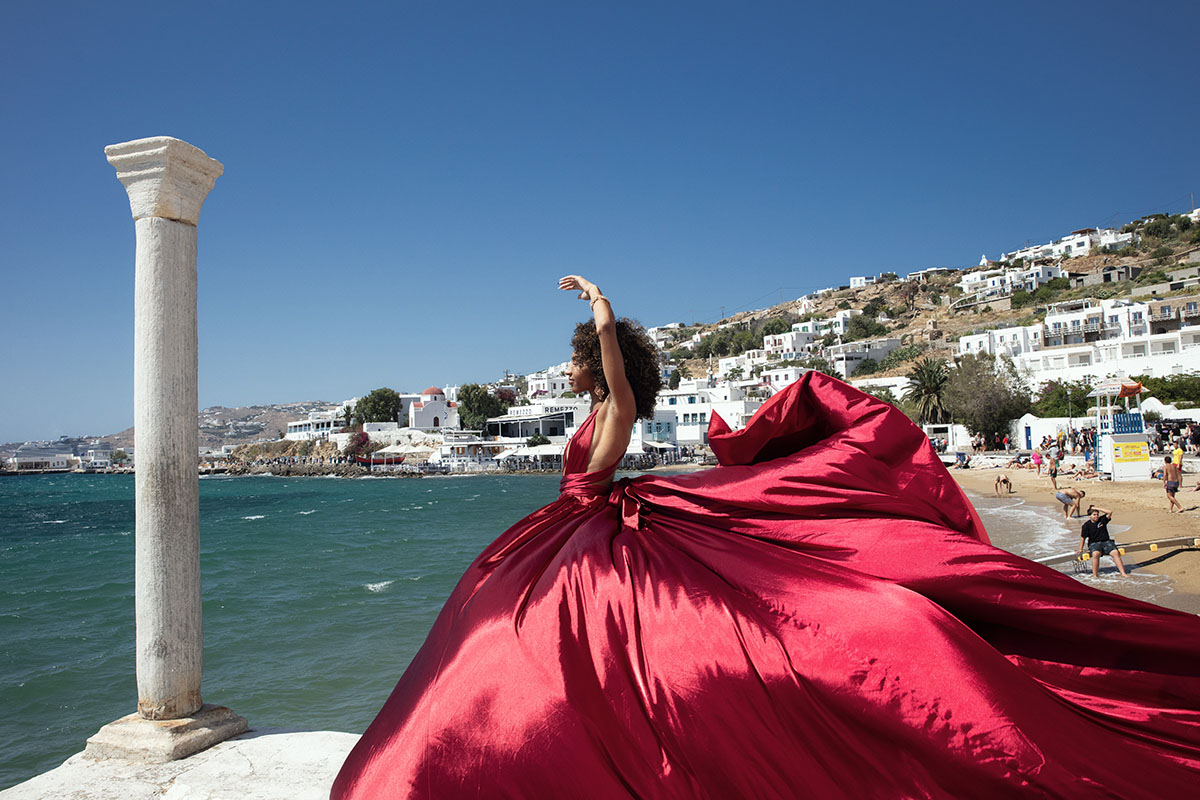 Sunlit sunset flying dress by Cycladic walls, photography in Mykonos, Greece