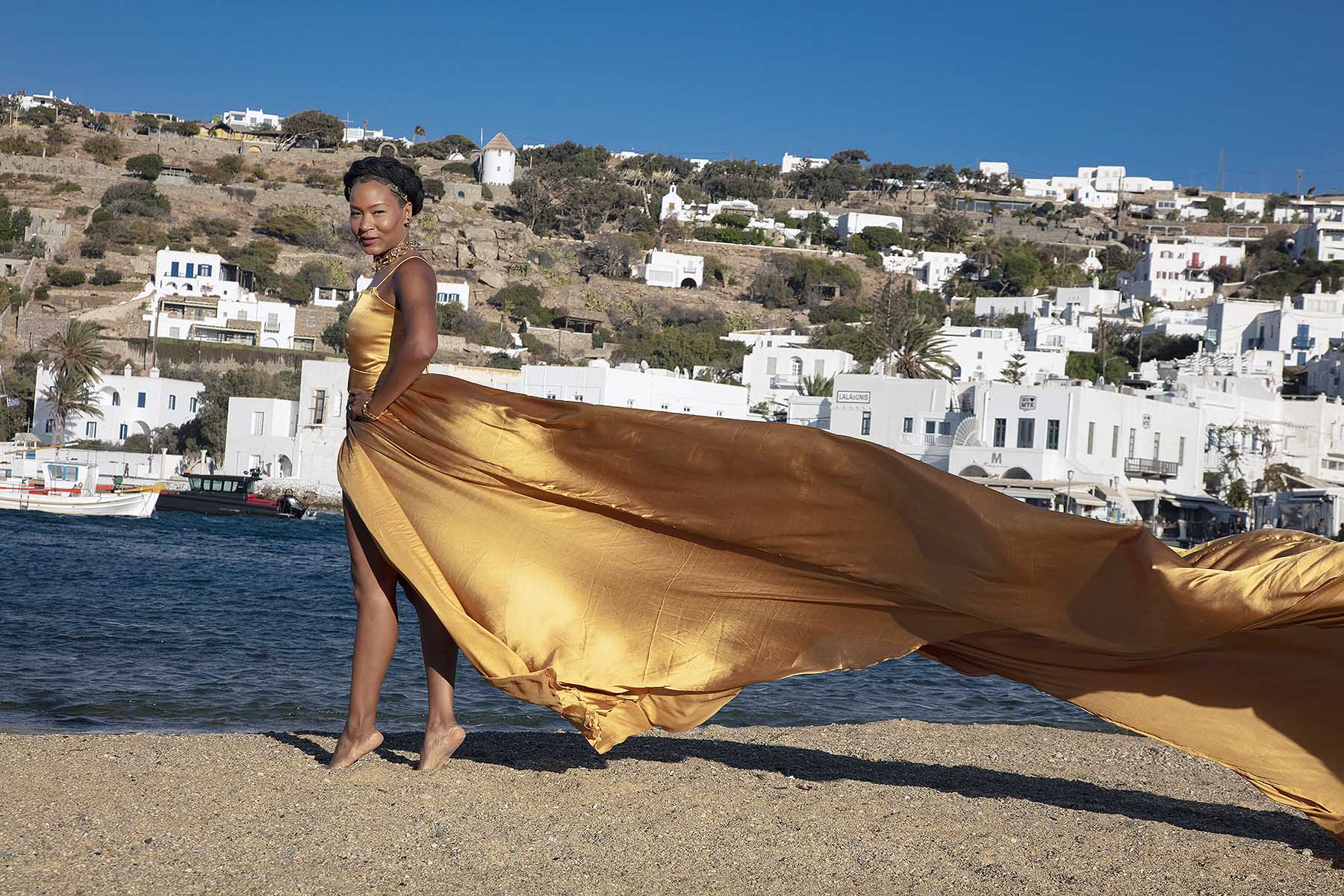 Sunlit sunset flying dress near a whitewashed chapel, photography in Mykonos, Greece