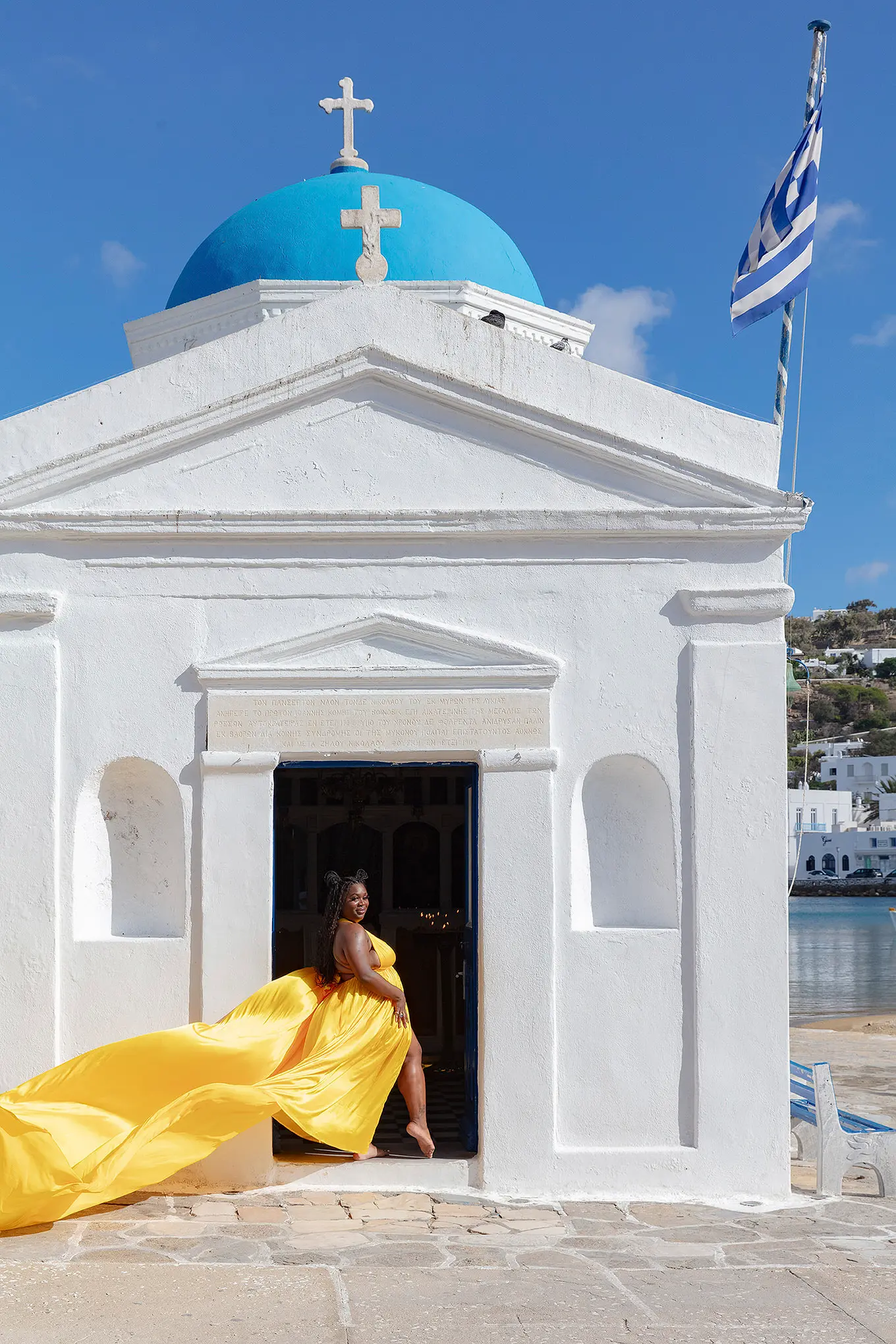 Sunlit teal flying dress in a Mykonos alley, photography in Mykonos, Greece