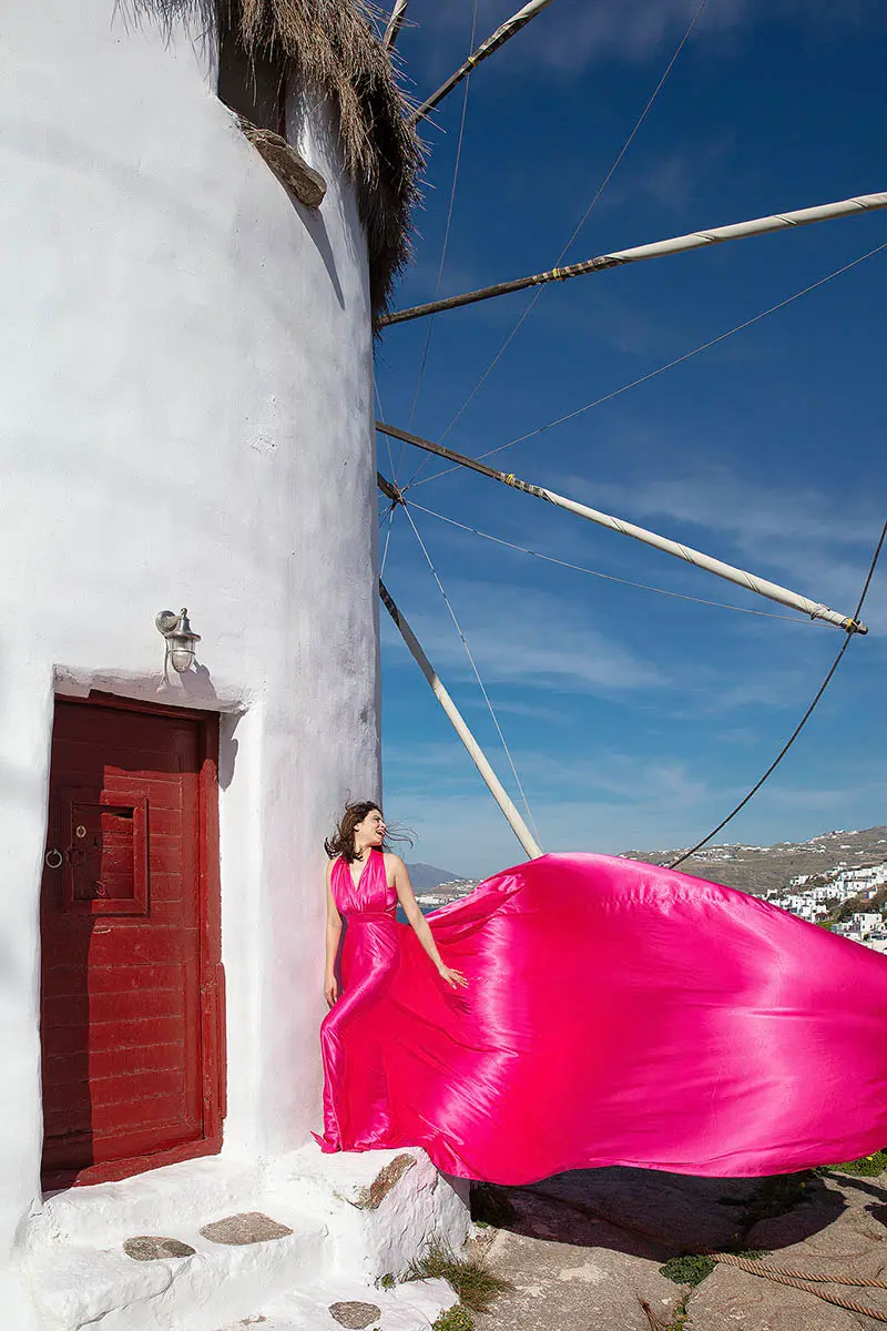 Sunlit teal flying dress by the Aegean sea, photography in Mykonos, Greece