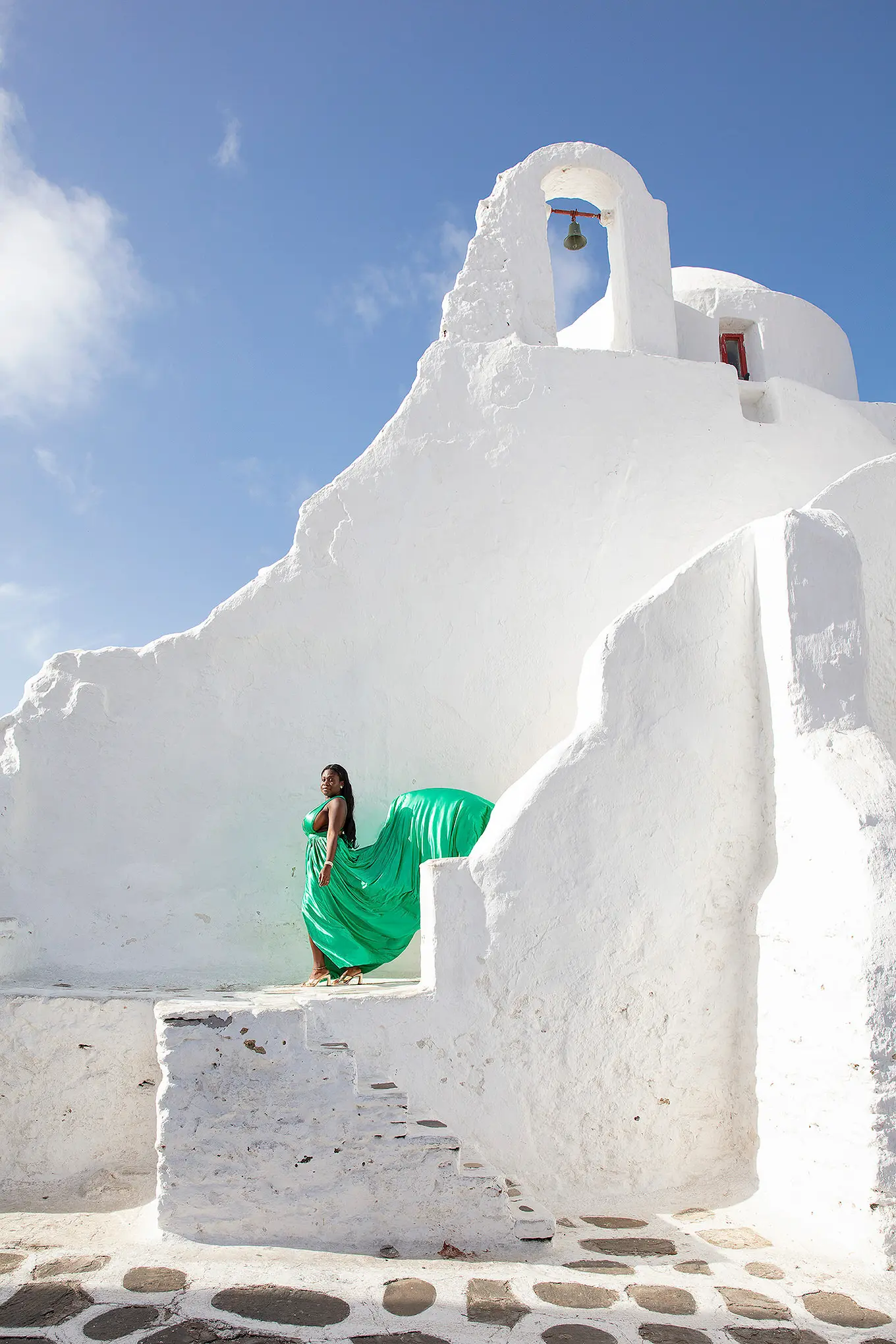 Sunlit teal flying dress by a blue door, photography in Mykonos, Greece