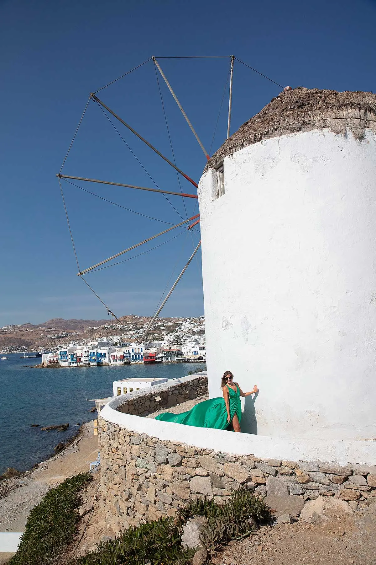 Sunlit red flying dress at white Mykonos chapel in a Mykonos alley, photography in Mykonos, Greece
