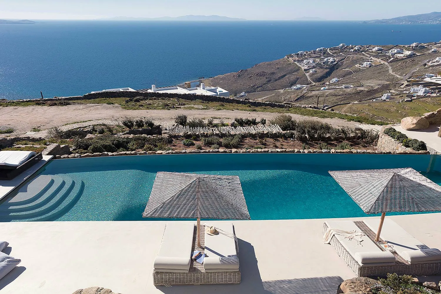 Sunlit infinity pool hotels villas advertising moment in Mykonos, Greece