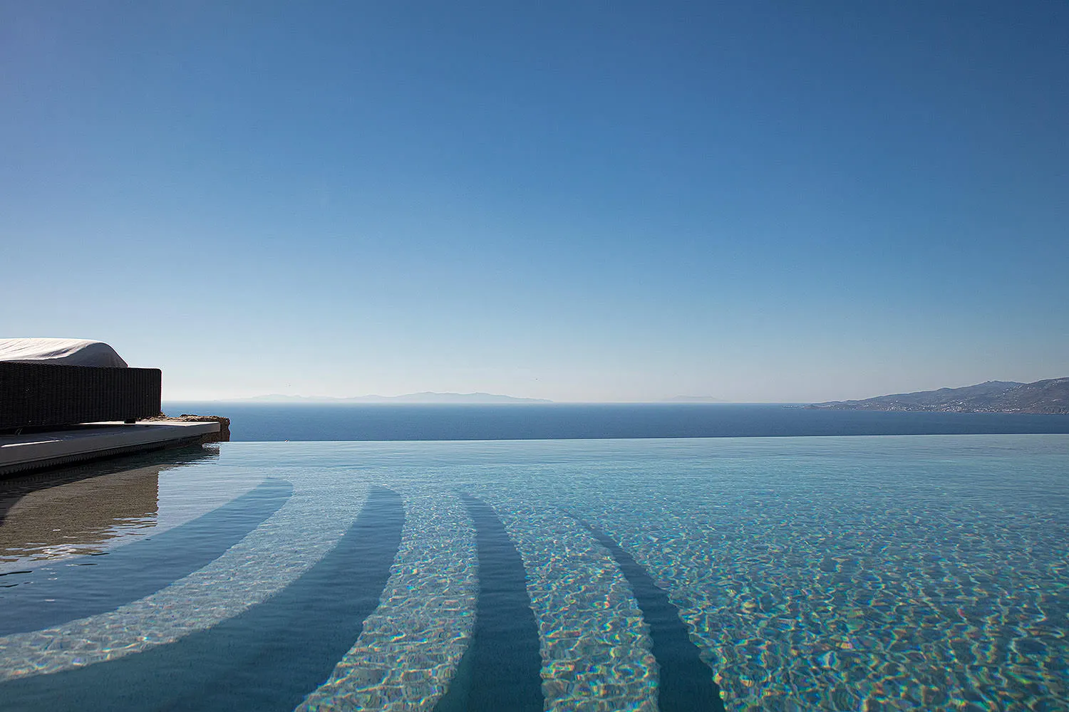 Sunlit infinity pool hotels villas advertising composition in Mykonos, Greece