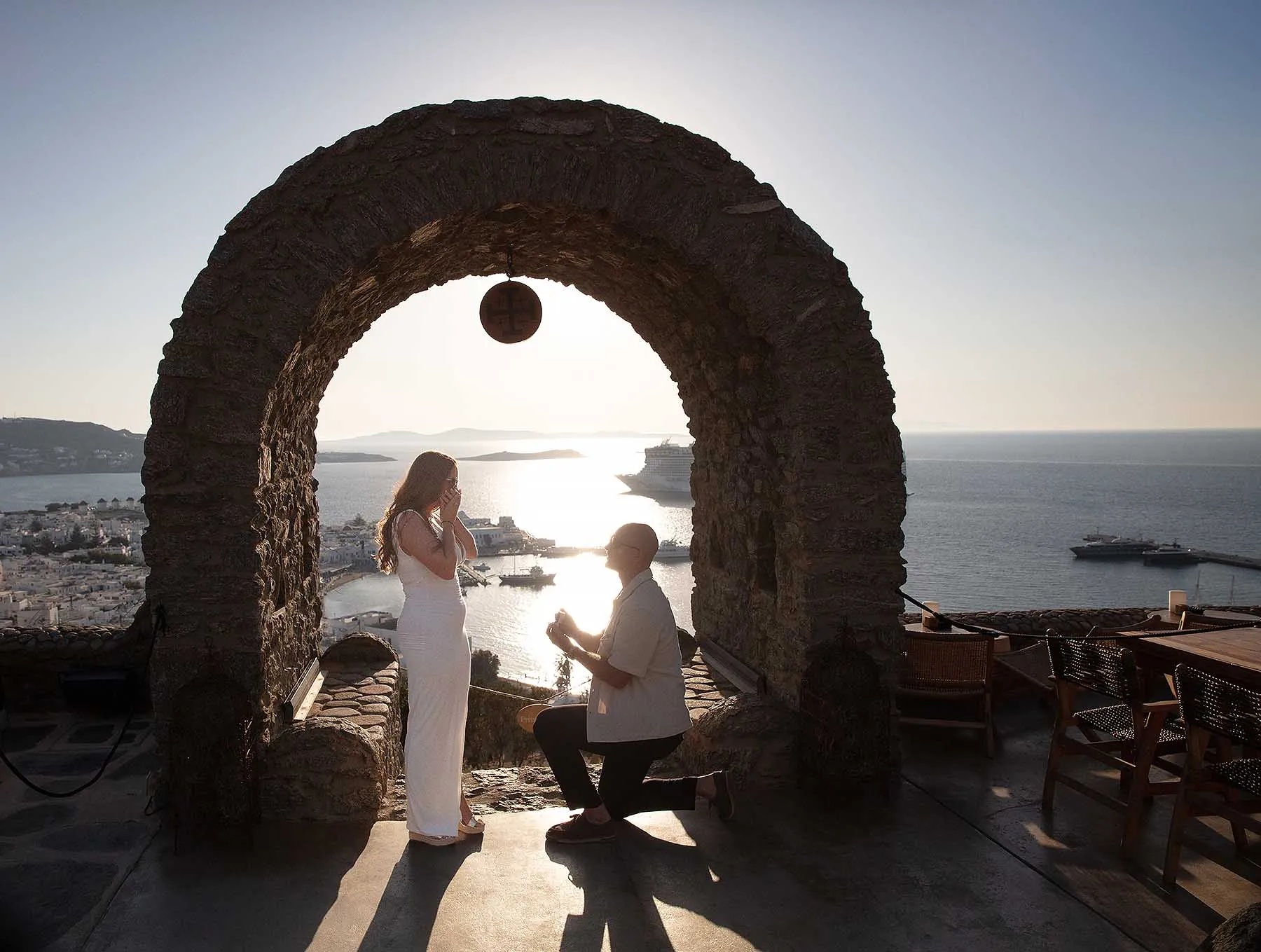 Sunlit stone arch wedding proposal frame in Mykonos, Greece