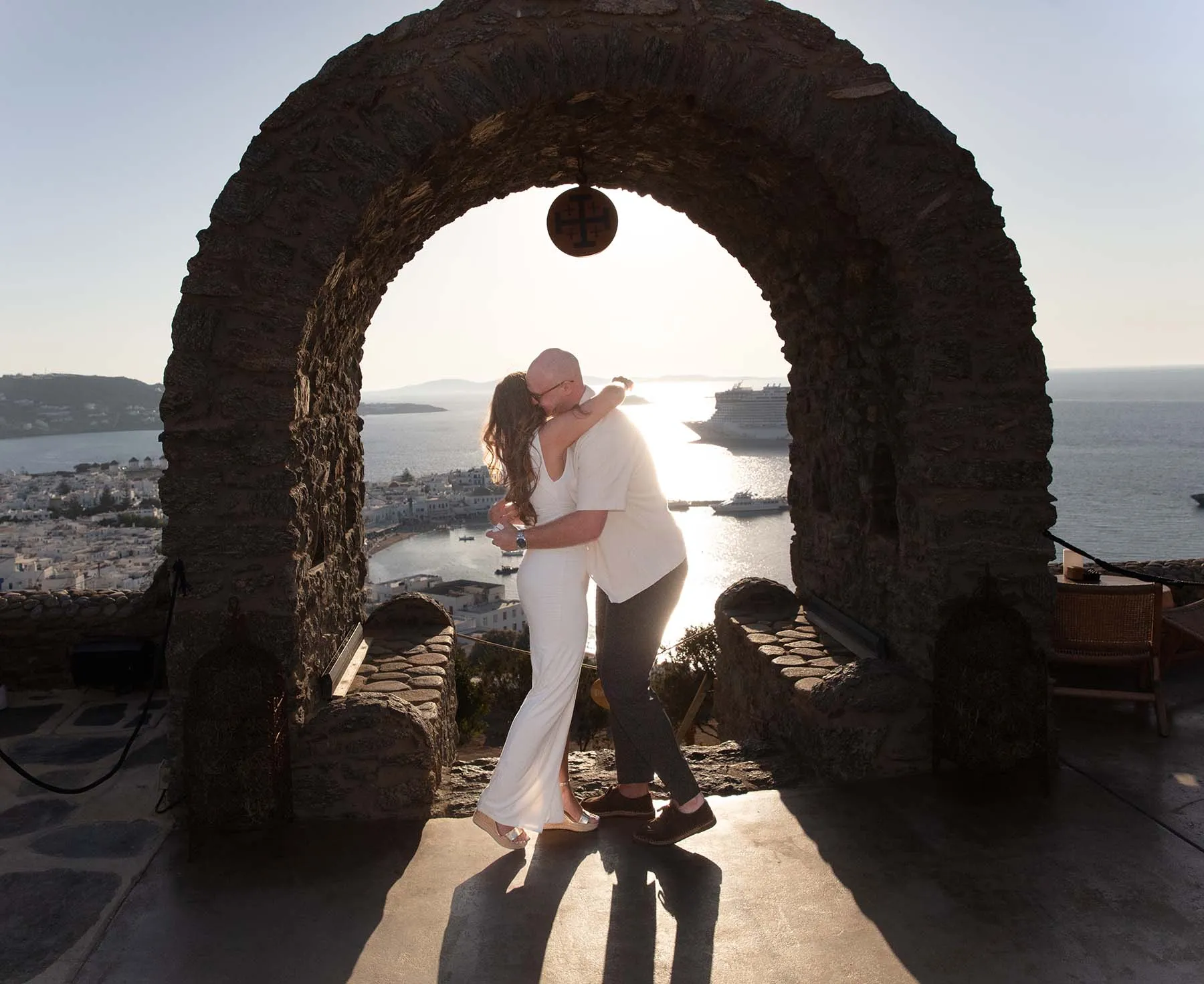 Sunlit stone arch wedding proposal view in Mykonos, Greece
