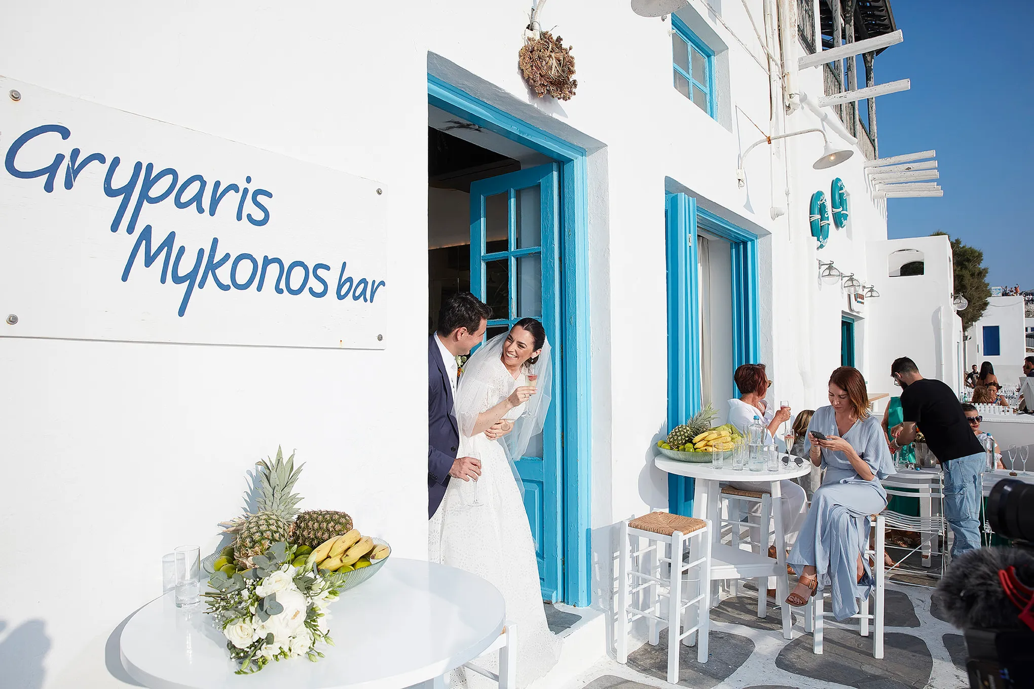 Sunlit aerial drone wedding photography by a blue dome, in Mykonos, Greece