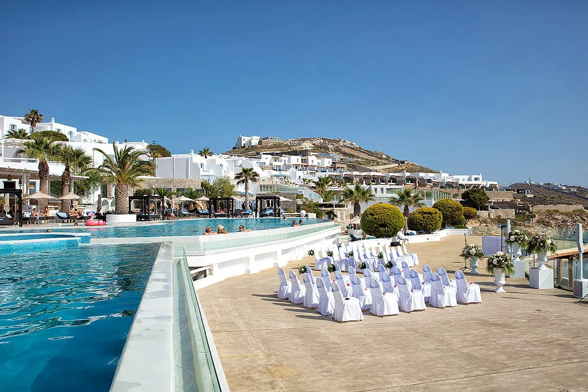 Sunlit beach wedding photography by a blue dome, in Mykonos, Greece