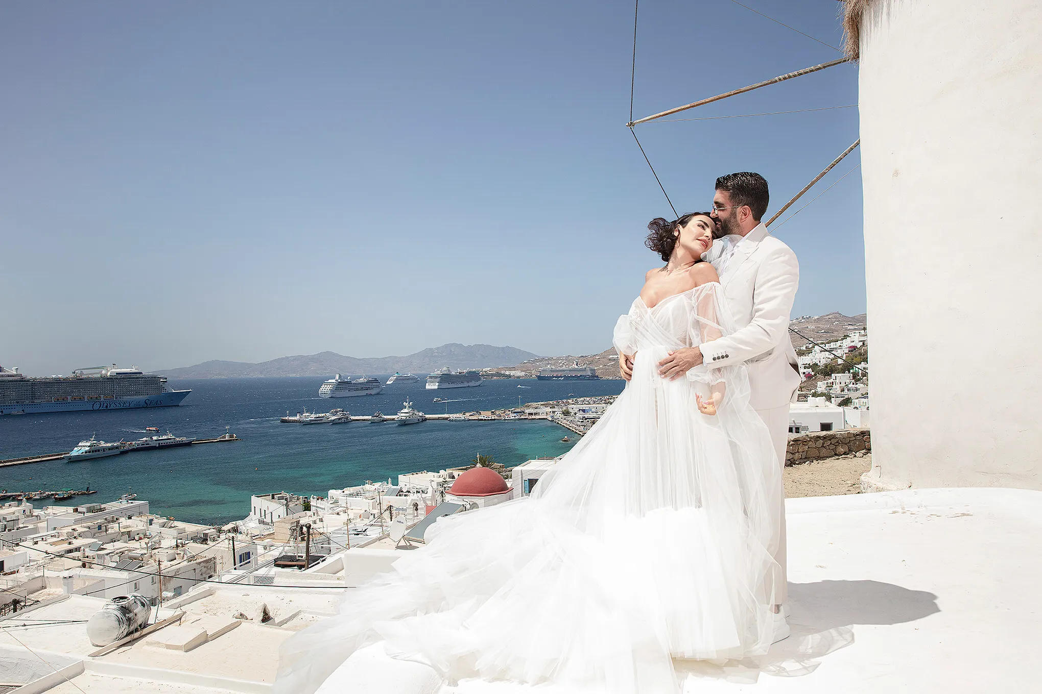 Sunlit candid wedding photography by a blue dome, in Mykonos, Greece