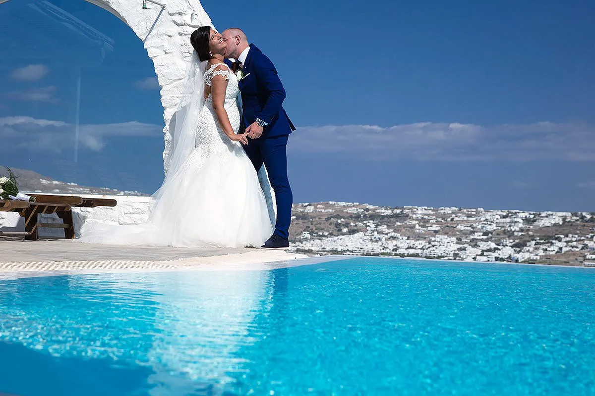 Sunlit chapel wedding photography by a blue dome, in Mykonos, Greece