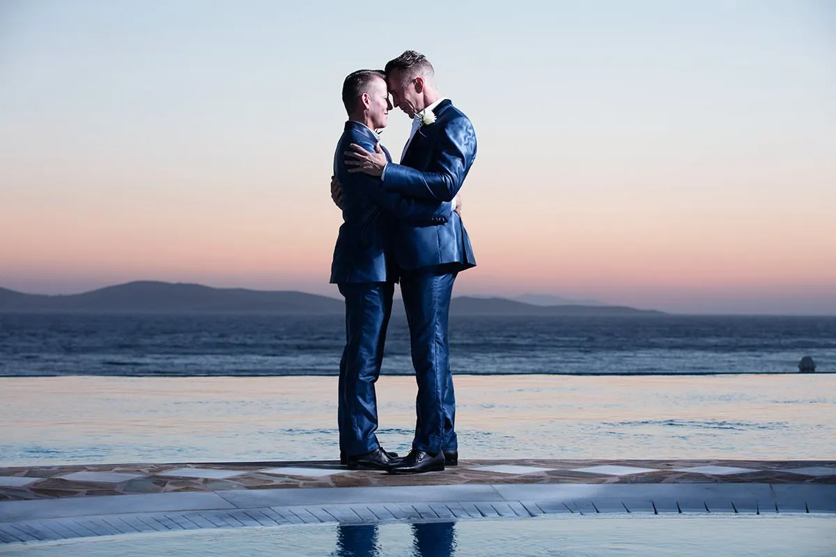 Sunlit monochrome wedding photography by a blue dome, in Mykonos, Greece
