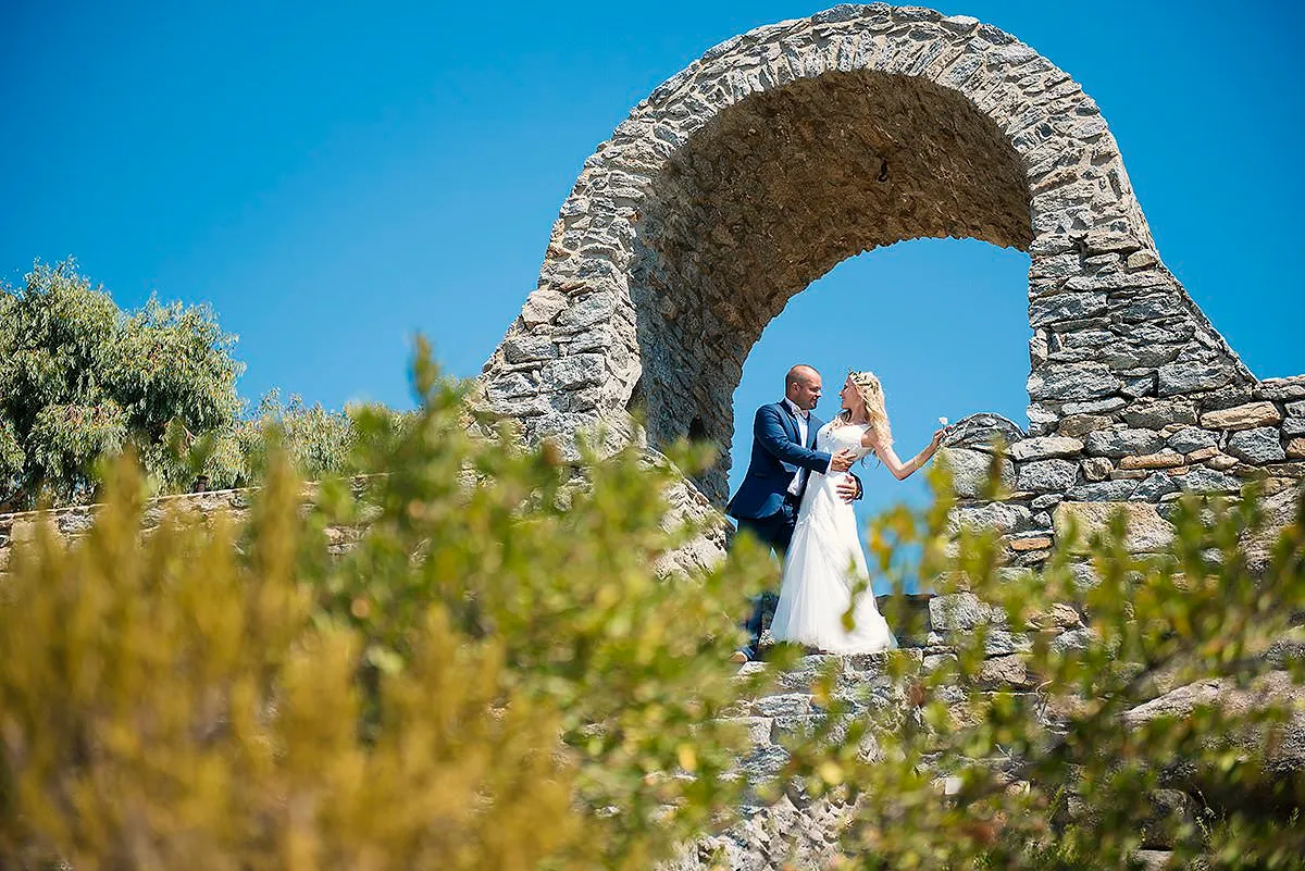 Sunlit vows wedding photography by a blue dome, in Mykonos, Greece